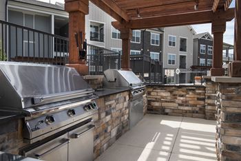 an outdoor kitchen with stainless steel appliances and a patio  at Watermark at Harvest Junction, Longmont, CO